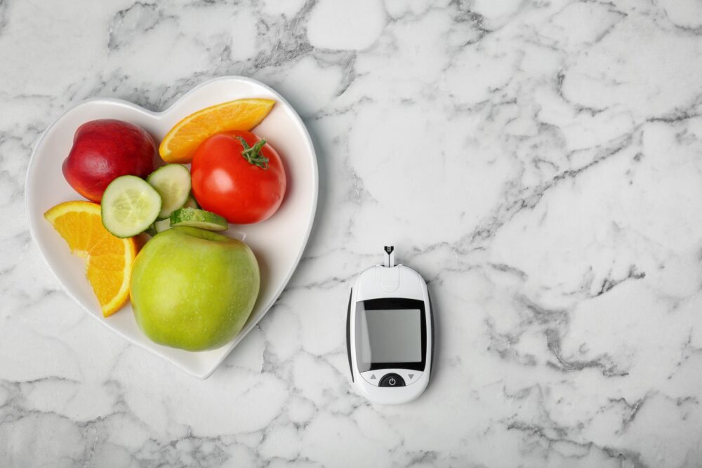 digital glucometer, fruits and vegetables on table.