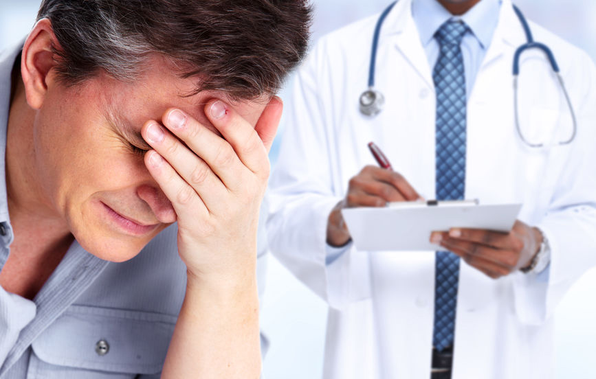 man holding his head with a doctor in the background